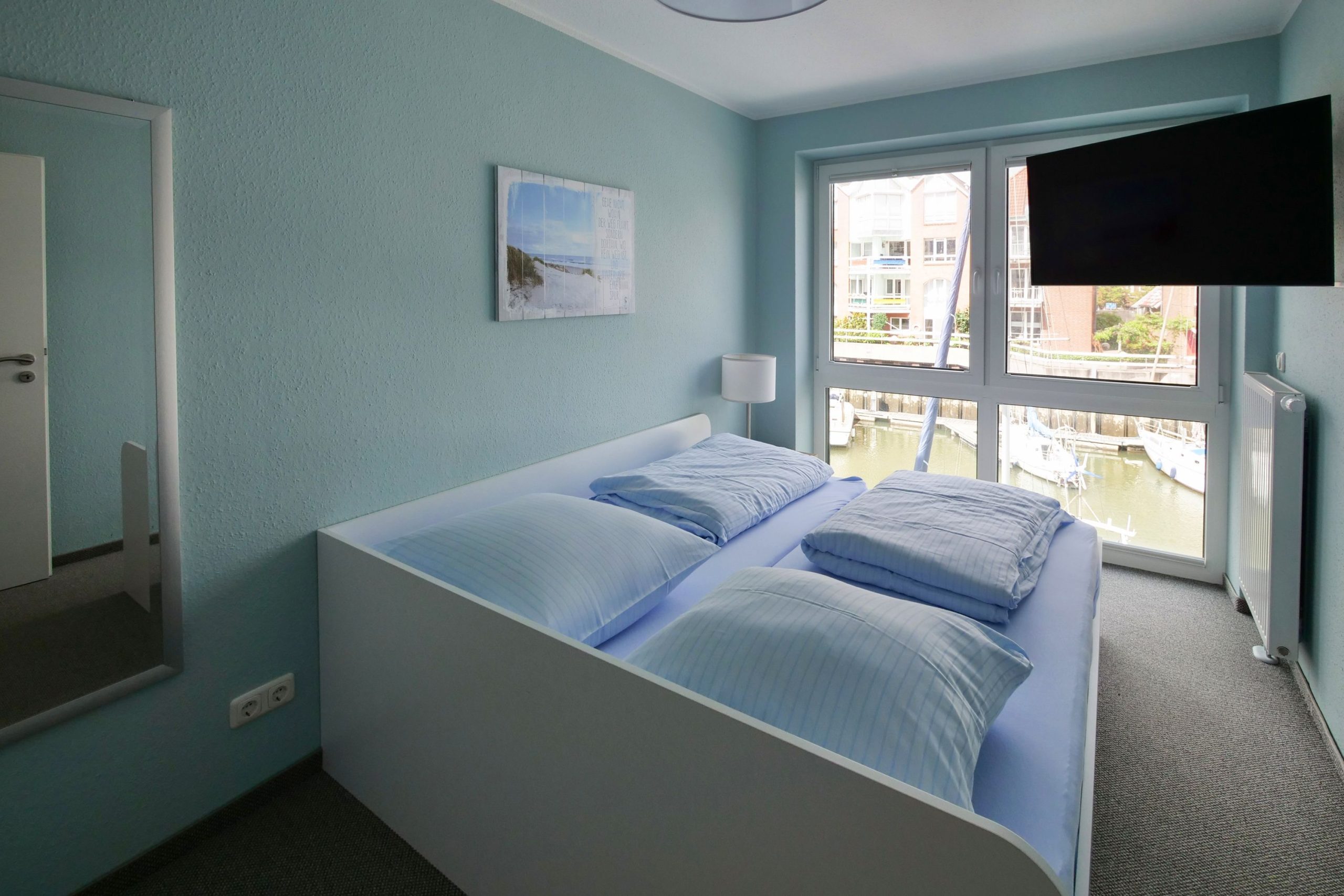 Schlafzimmer mit Doppelbett und drehbarem Fernseher in Ferienhaus in Cuxhaven
