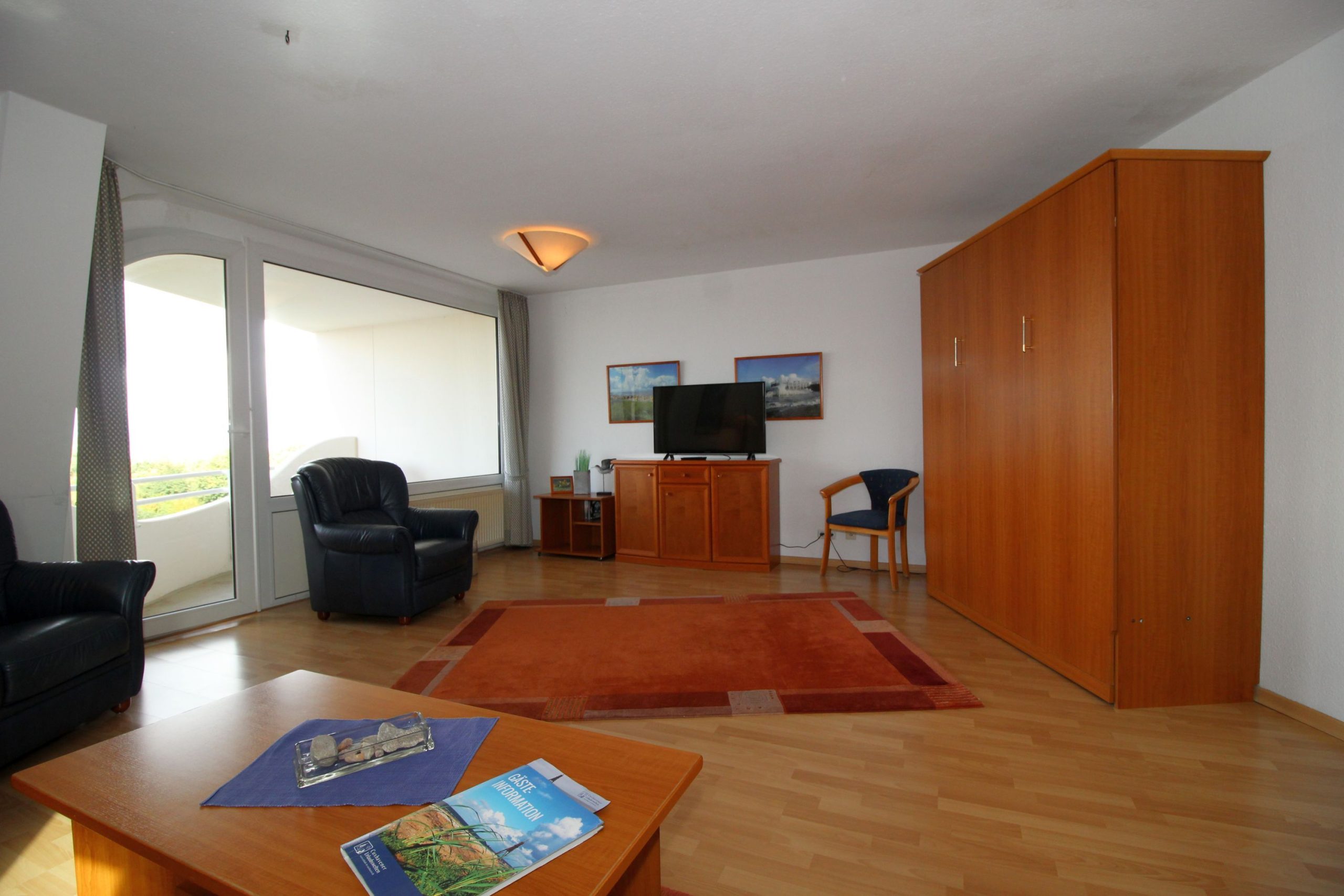 Wohnzimmer mit Schrank und Fernseher in Ferienwohnung in Cuxhaven