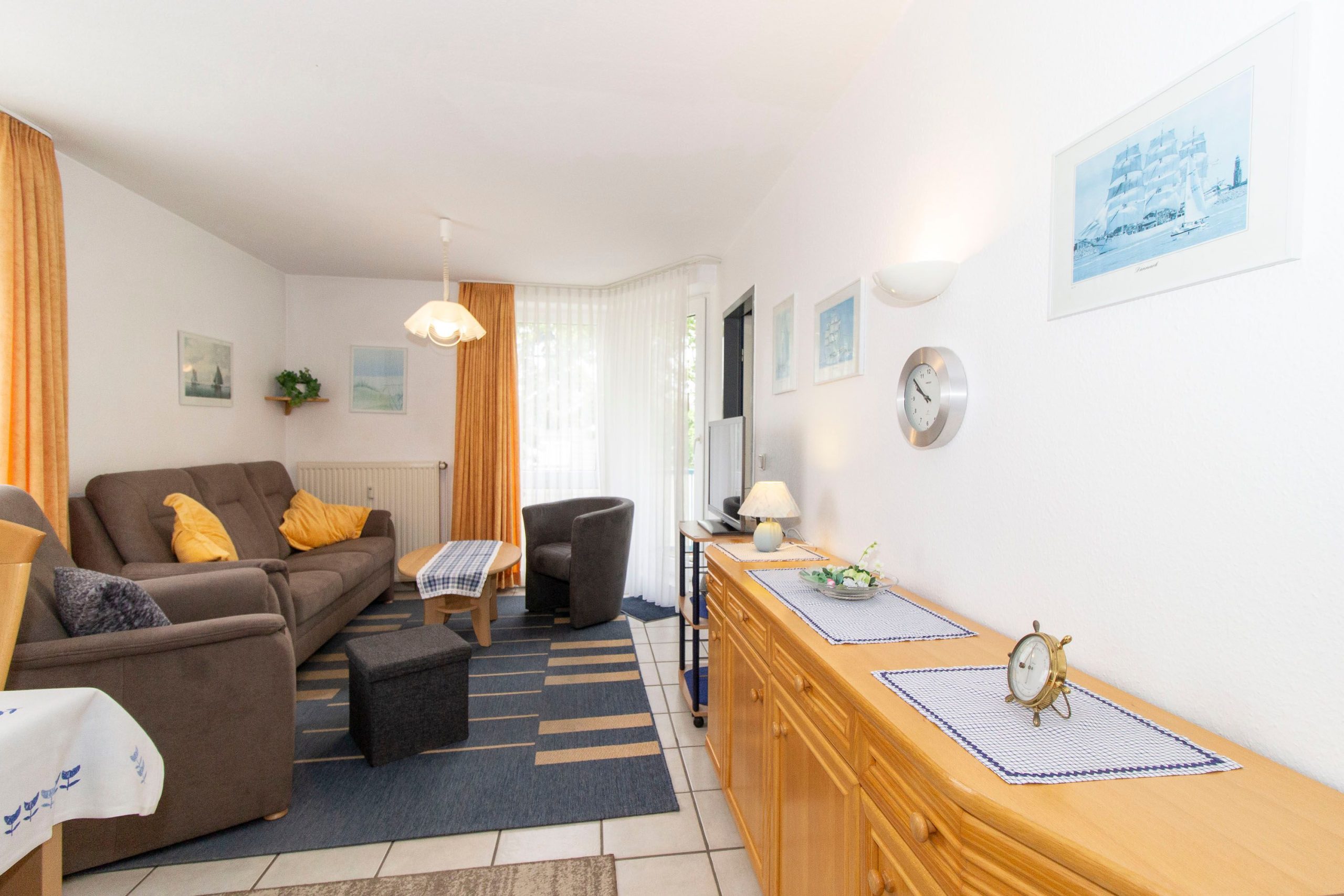 Wohnzimmer mit Fernseher und Sofa mit Sessel in Ferienwohnung in Cuxhaven